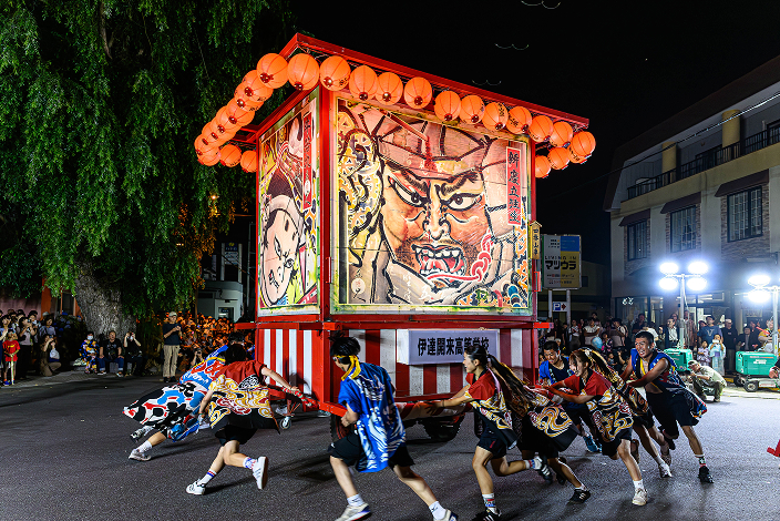 武者絵の描かれた山車を押して夜の街を駆ける高校生たち