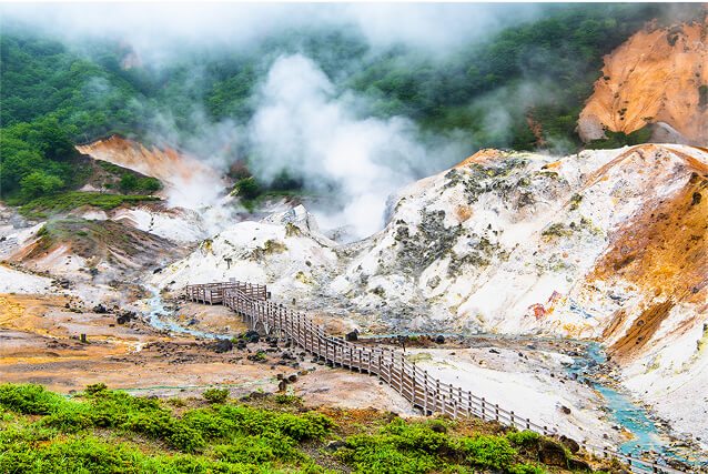 噴気が立つ岩肌の谷の風景